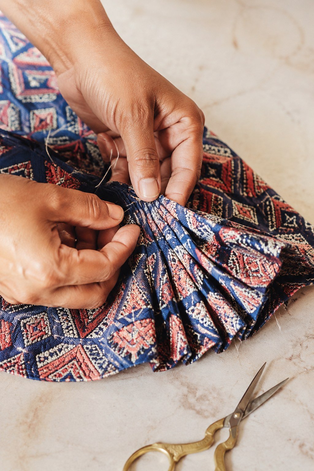 Hands stitching pleated geometric brocade fabric